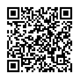 一个身穿灰色工人装的小老头正拿着把刨锯在刨一块厚木板二维码生成