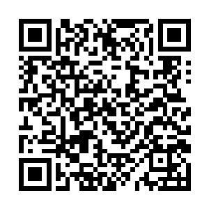 一位留着大背头的中年男子翘着二郎腿斜靠在椅子上二维码生成