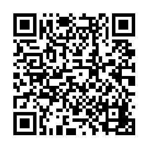 其中一个男人将一个针孔镜头摆放在对准床的地方二维码生成