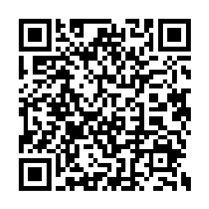 大冯曼坐在一张看起来有些歪歪扭扭的桌子后面二维码生成