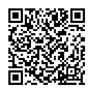 穿着宽大的孕妇服的少女坐在明亮的花厅中刺绣二维码生成