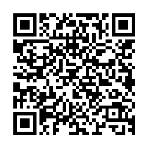 穿着棉布裙子的少女站在一块临时用几块小木板拼凑起来的桌旁二维码生成